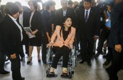 Thailand's Prime Minister Yingluck Shinawatra arrives on a wheelchair at the Royal Police Cadet Academy in Nakorn Pathom province