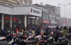 People gather in front of a branch of Jiangsu Sheyang Rural Commercial Bank, in Yancheng